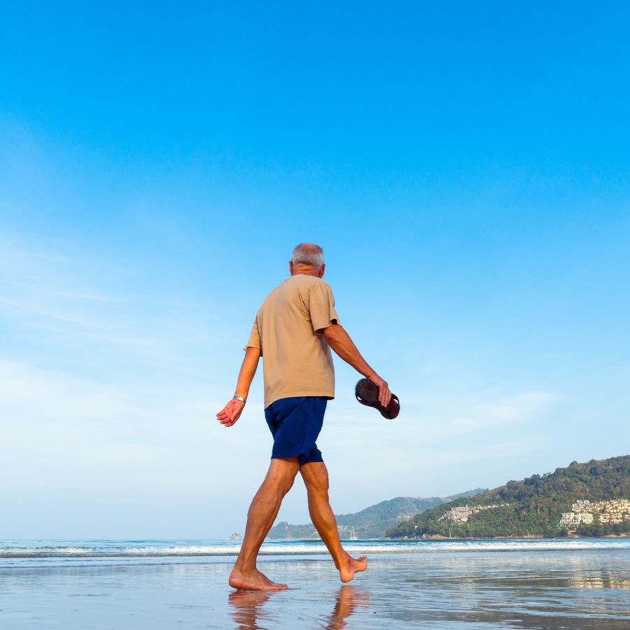 older adult walking on beach